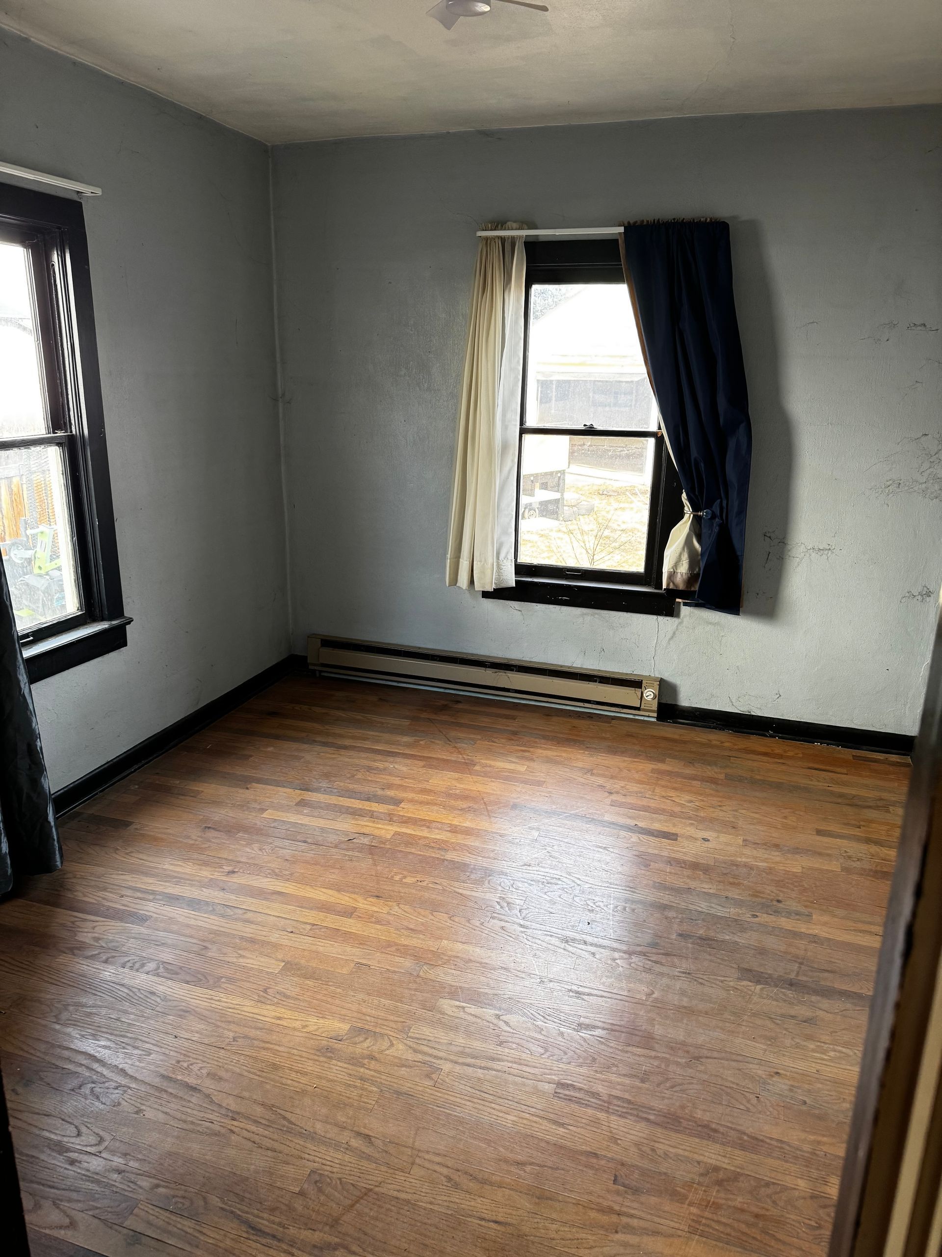 Wooden fence with two trash bins next to it on a concrete pad.