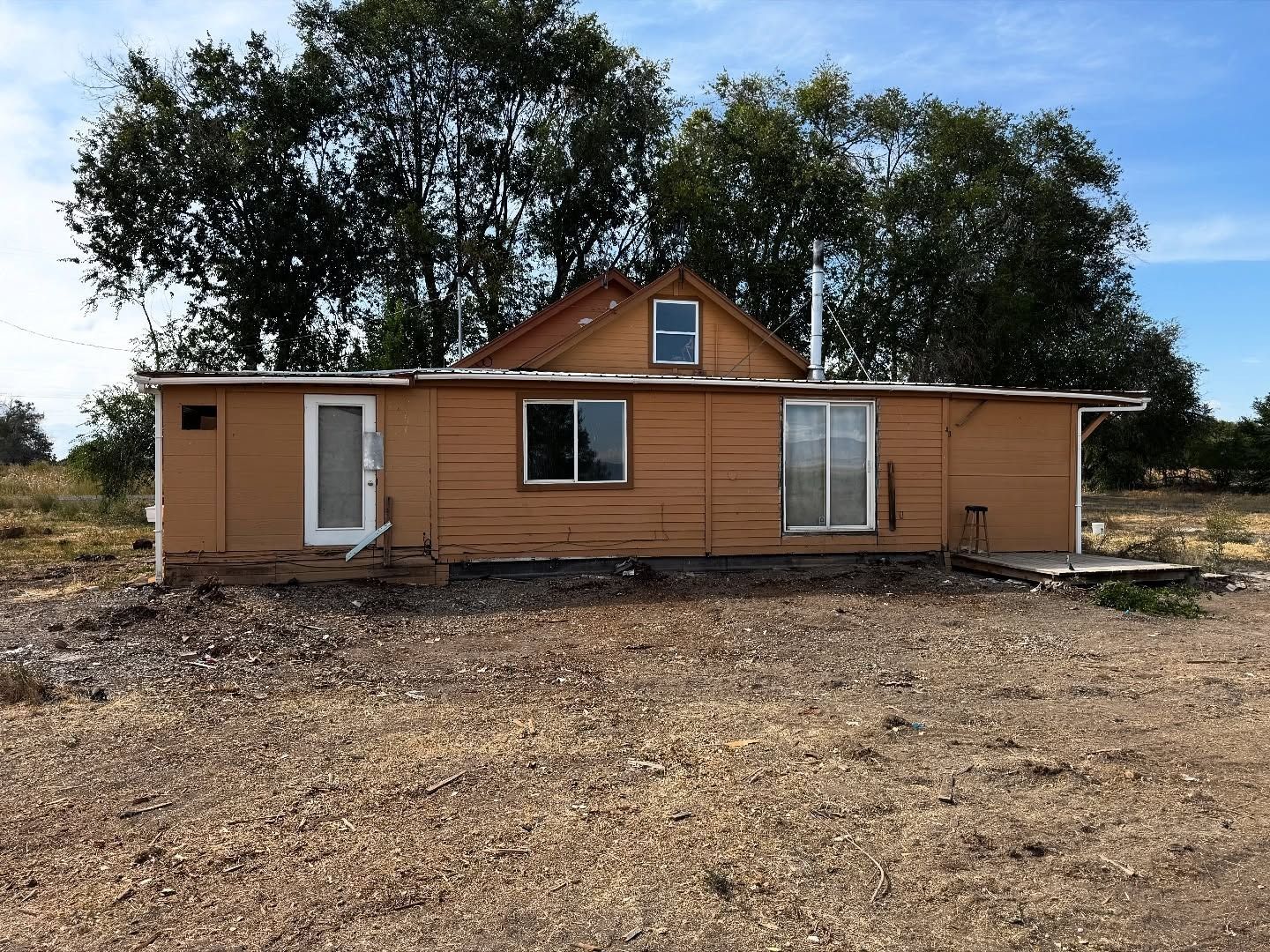 Two-story house with dark roof, white garage door, and brick and tan siding on a cloudy day.