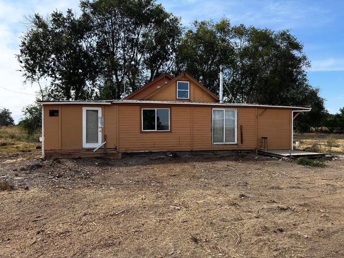 Two-story house with dark roof, white garage door, and brick and tan siding on a cloudy day.