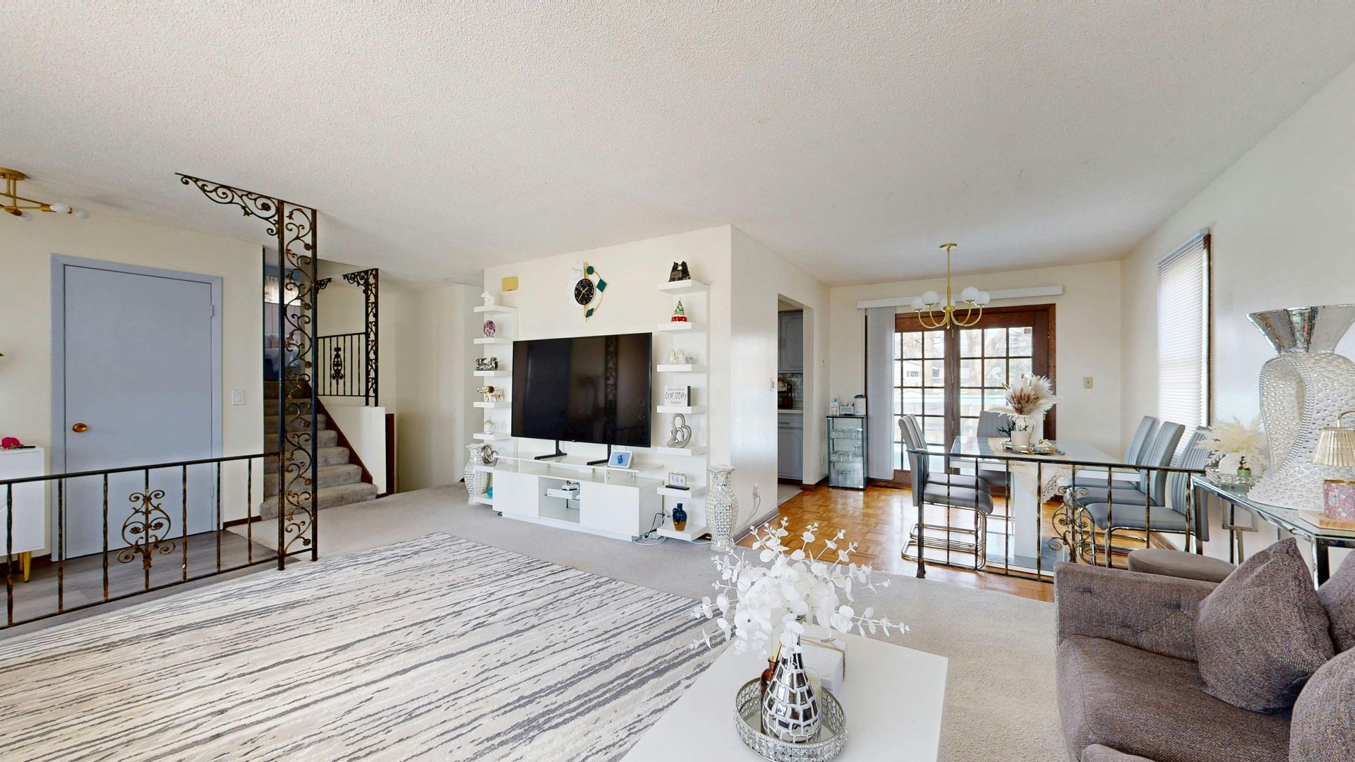 Dilapidated brown house with a destroyed wooden deck and overgrown weeds.