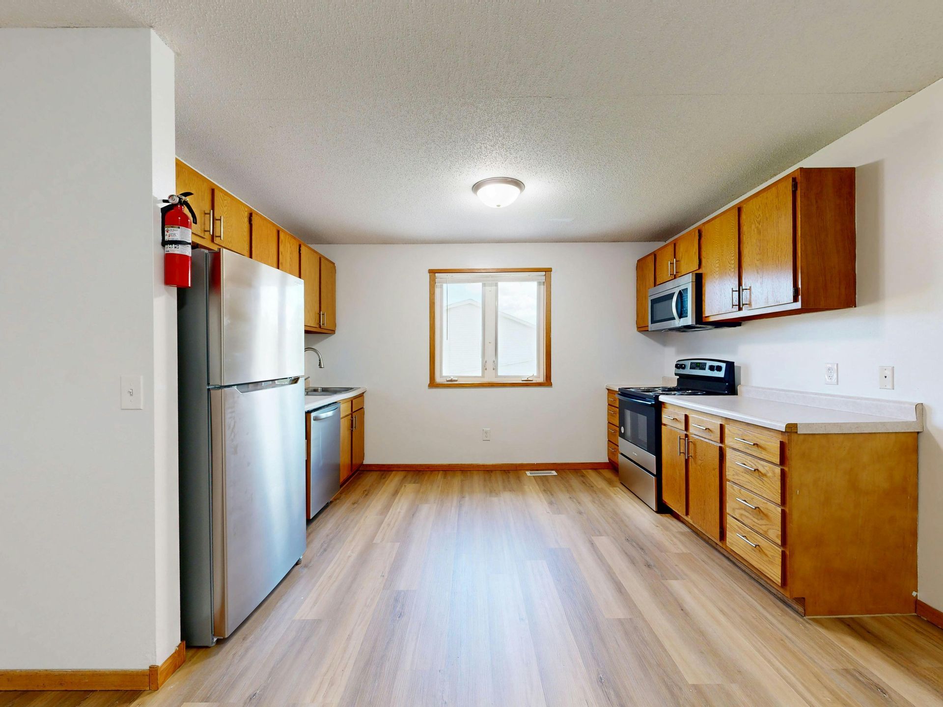 Dilapidated brown house with a destroyed wooden deck and overgrown weeds.