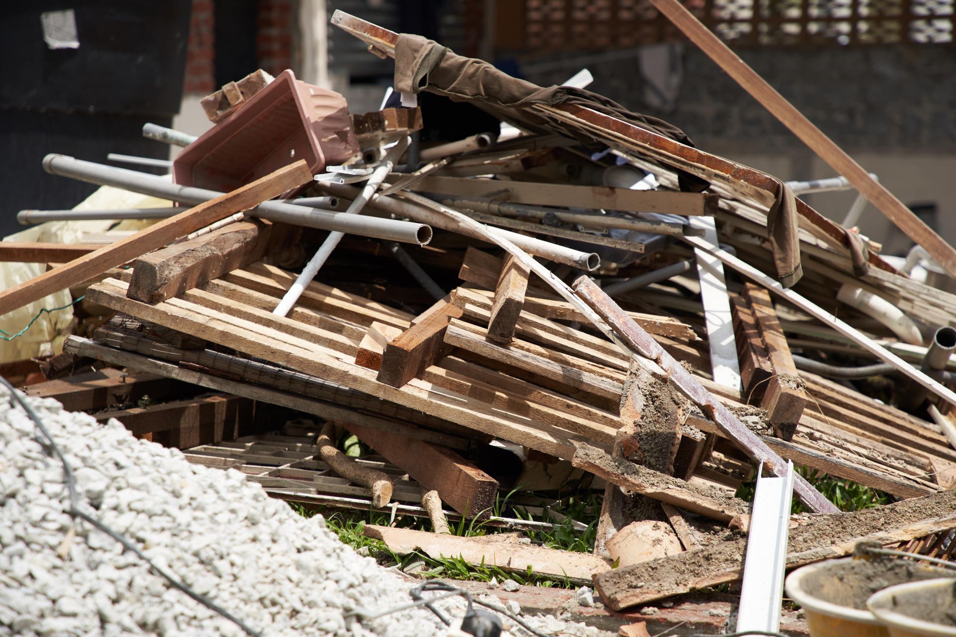 Pile of construction debris including wood planks, metal pipes, and concrete aggregate.