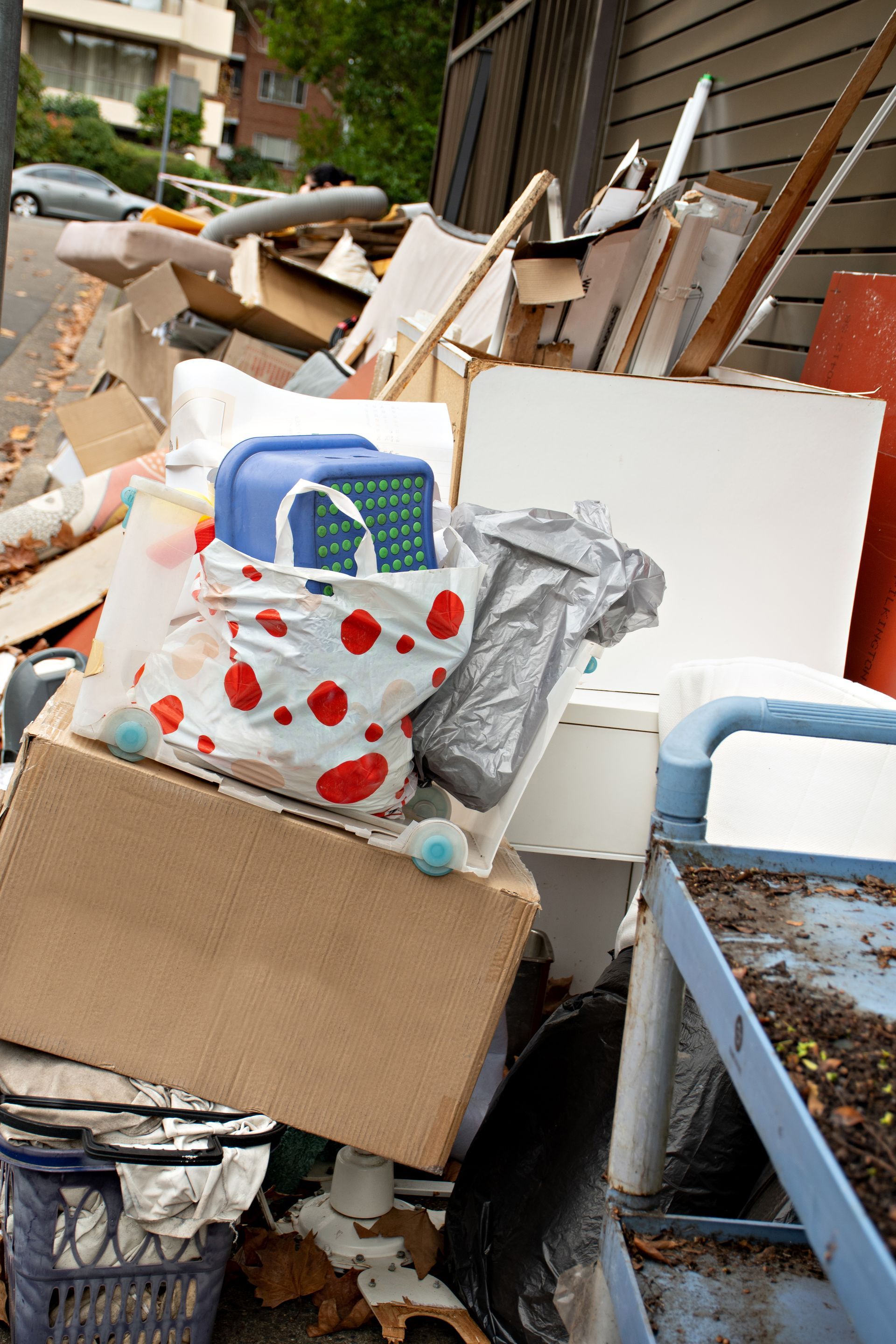 Pile of discarded items, including boxes, bags, and furniture, on a city street.