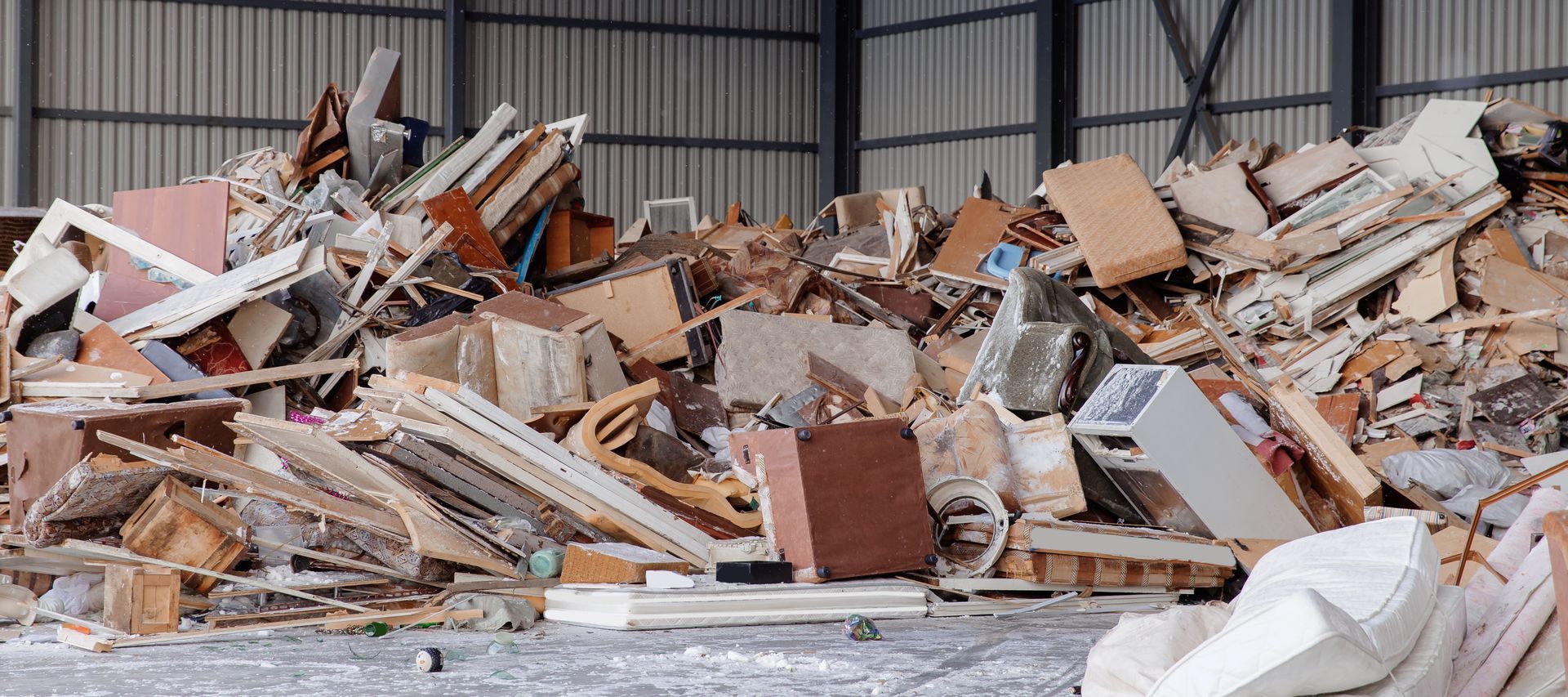 Pile of discarded furniture and debris inside a warehouse.