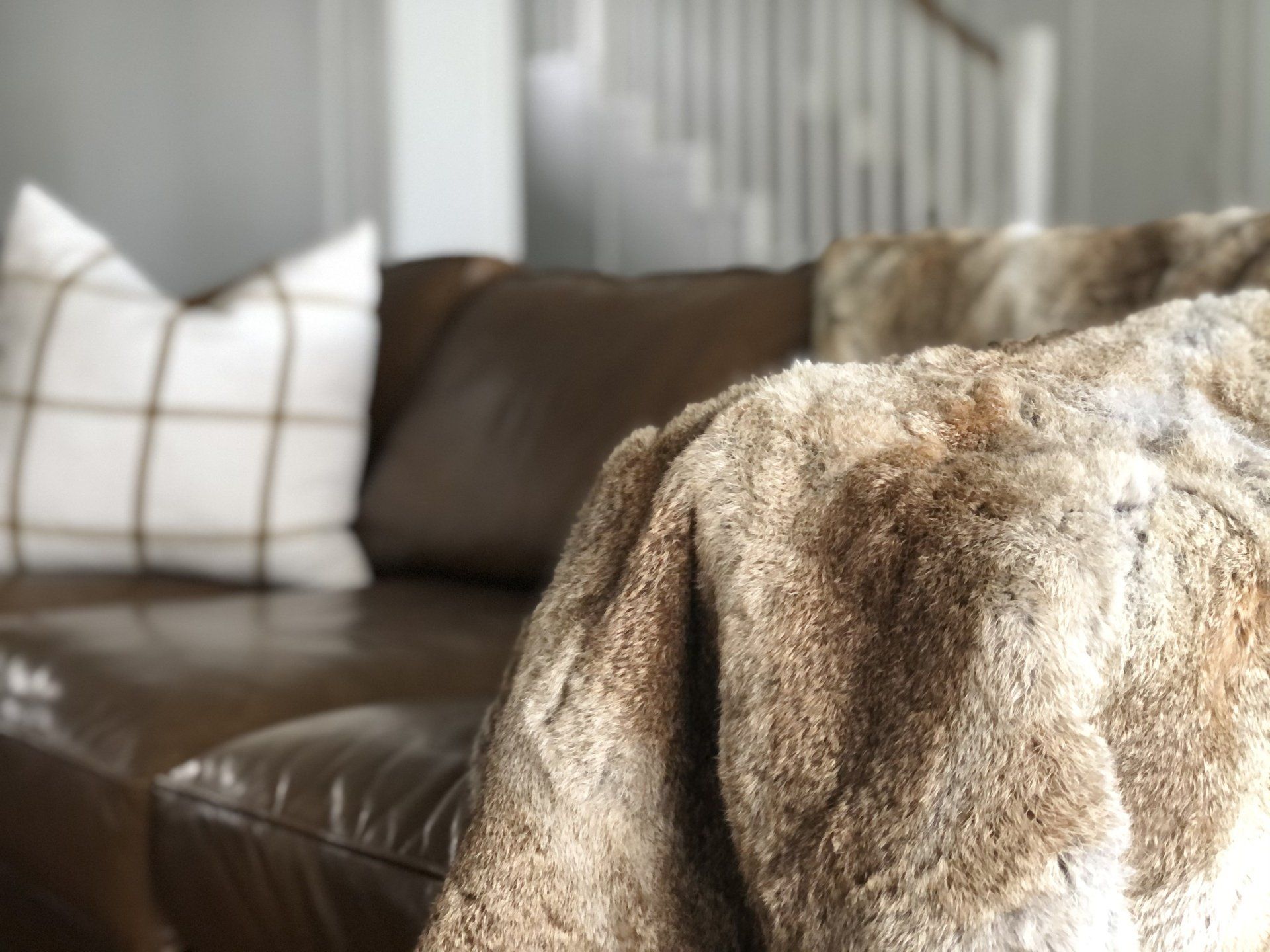 A brown leather couch with a fur blanket on it