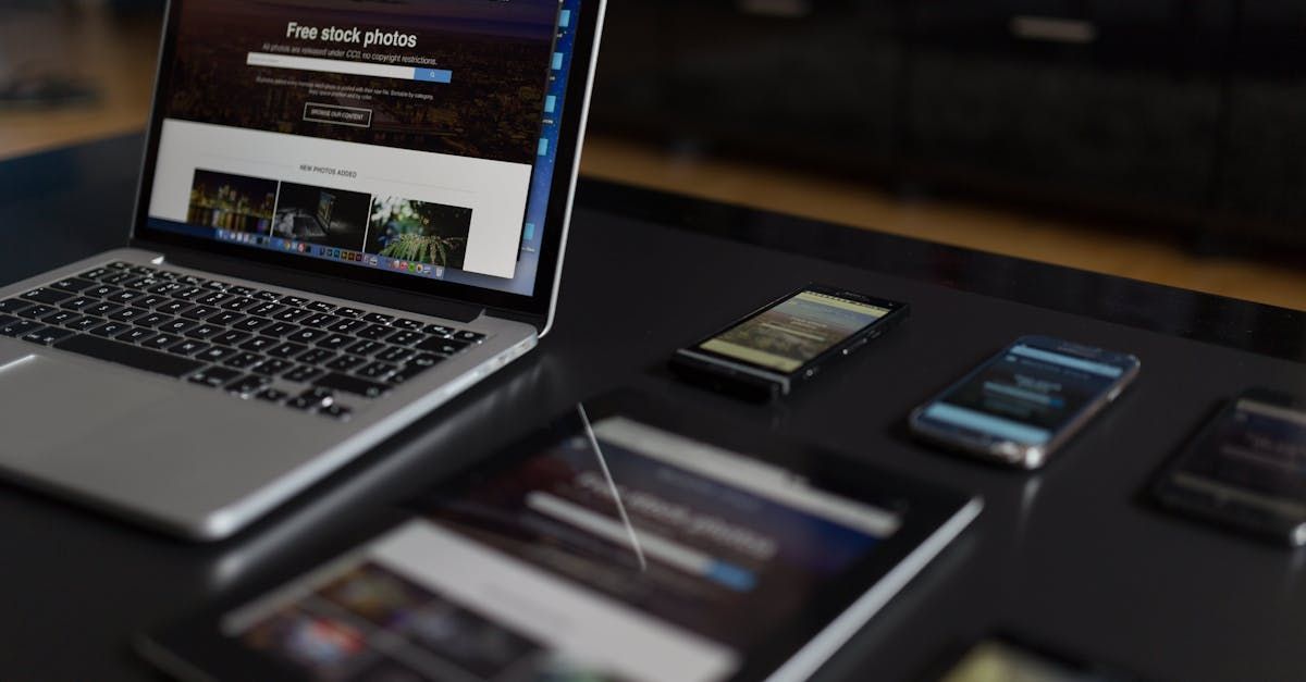 A laptop computer is sitting on top of a table next to a tablet and a cell phone.