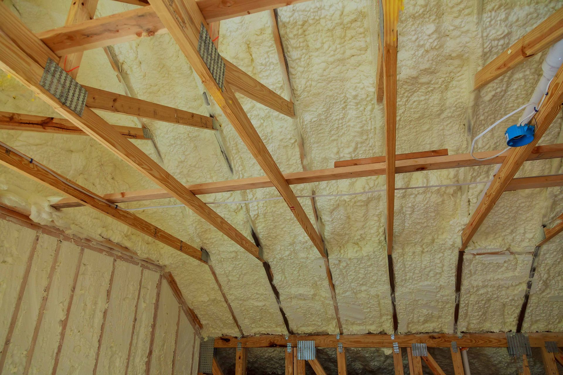 Interior of attic with spray foam insulation between wooden rafters.
