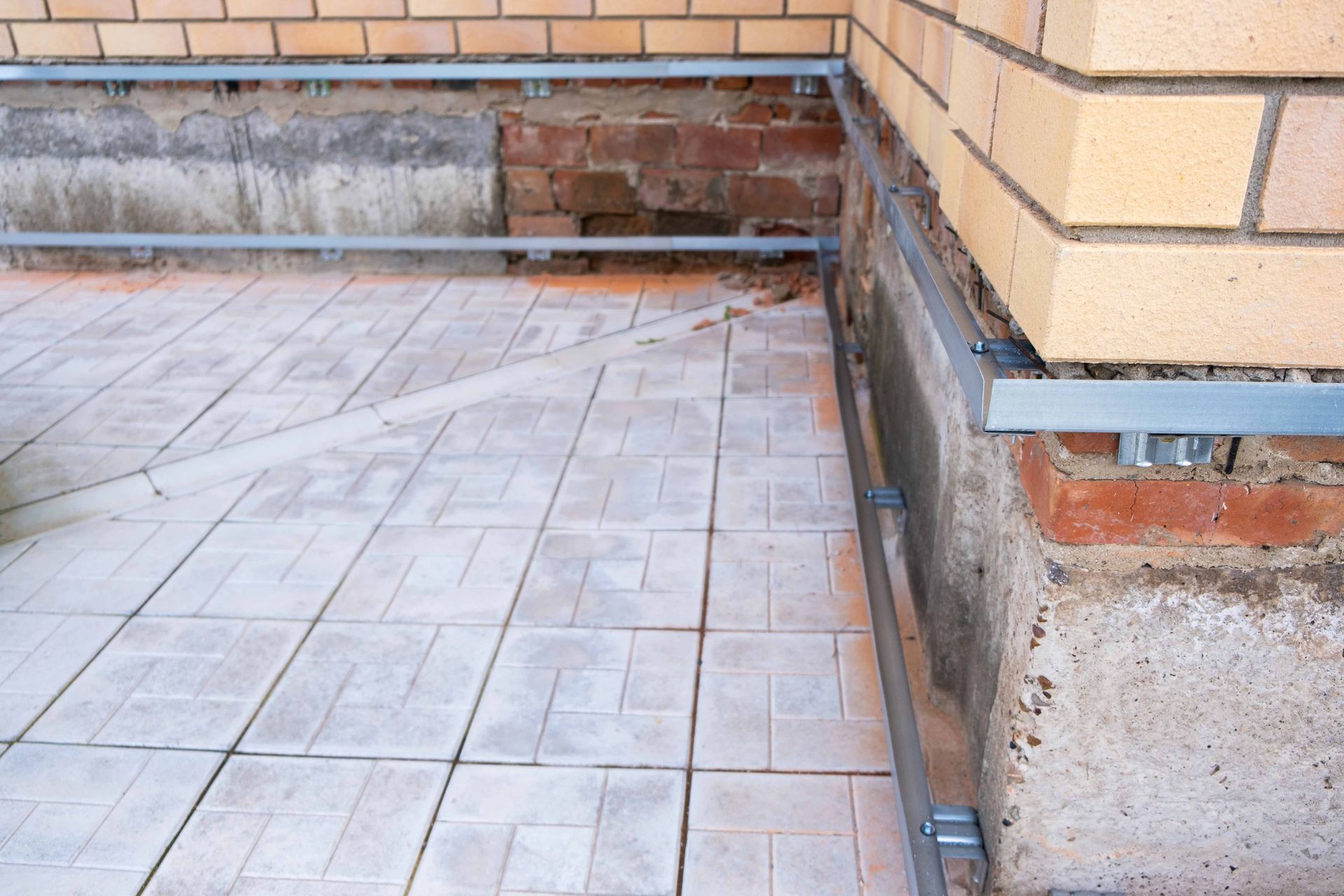 Brick wall corner with light-colored tile flooring and metal edging.