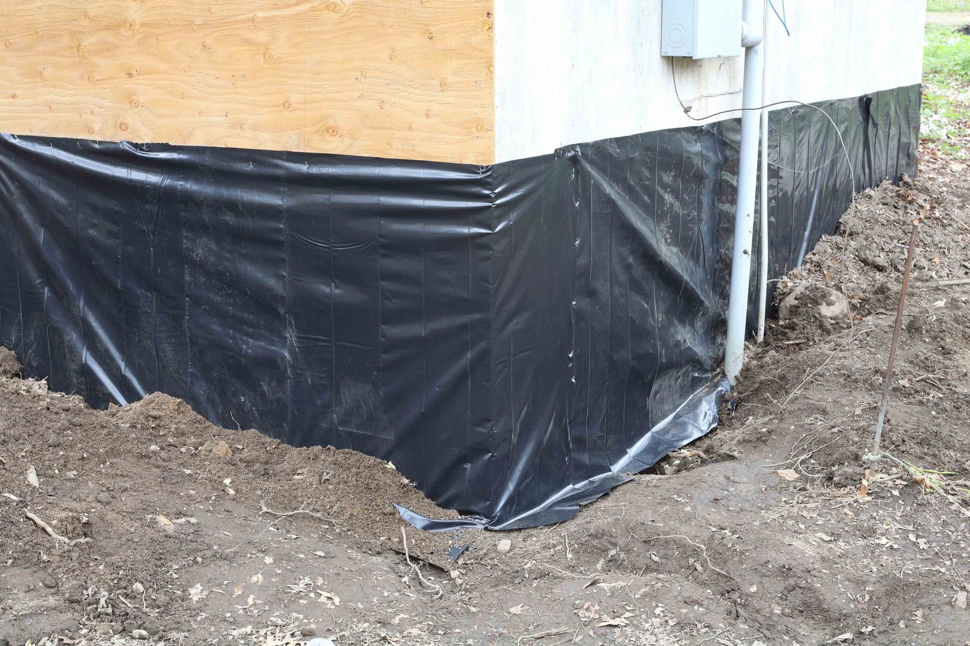 Black plastic sheeting wraps the foundation of a building.