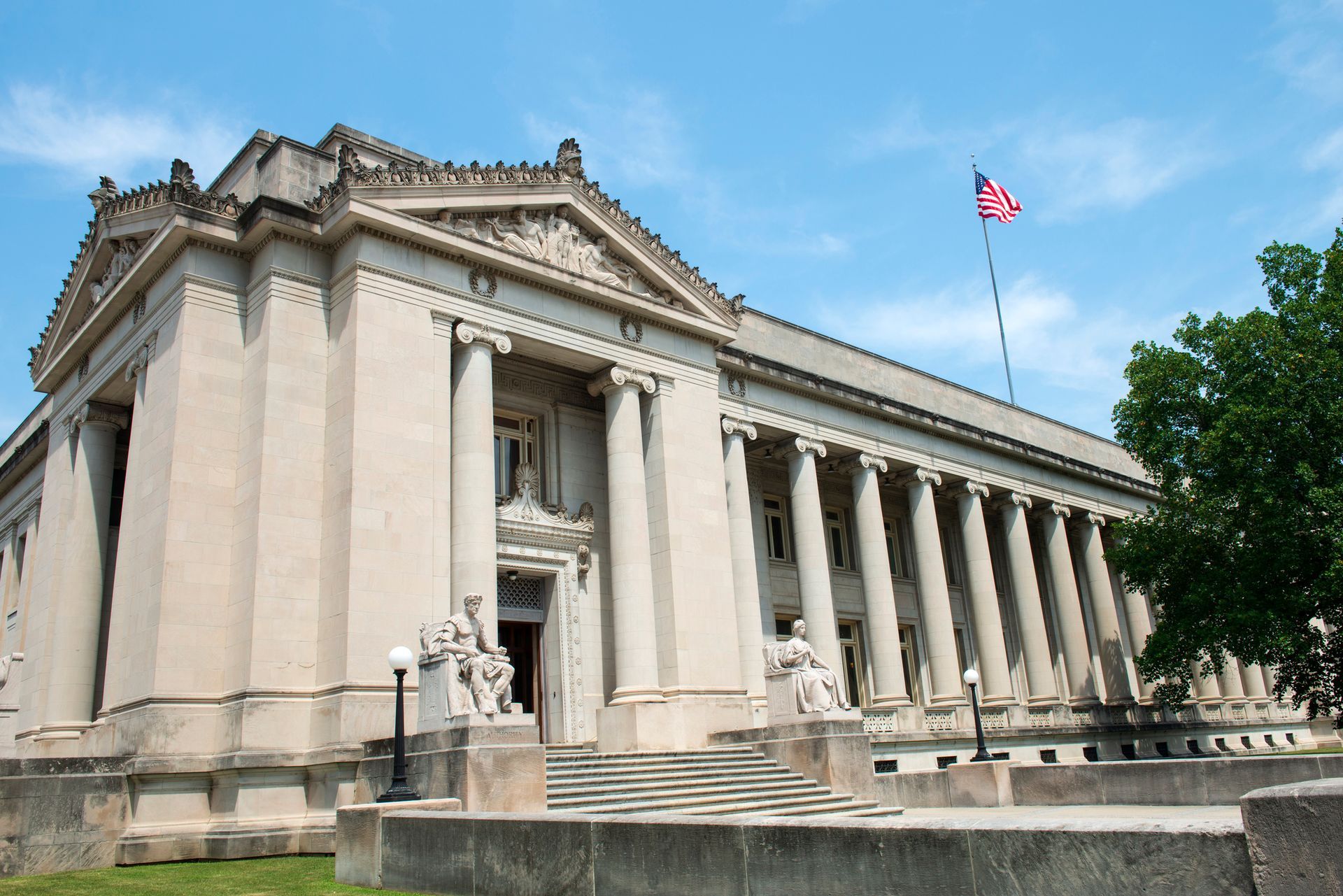 A large building with columns and an american flag flying in front of it