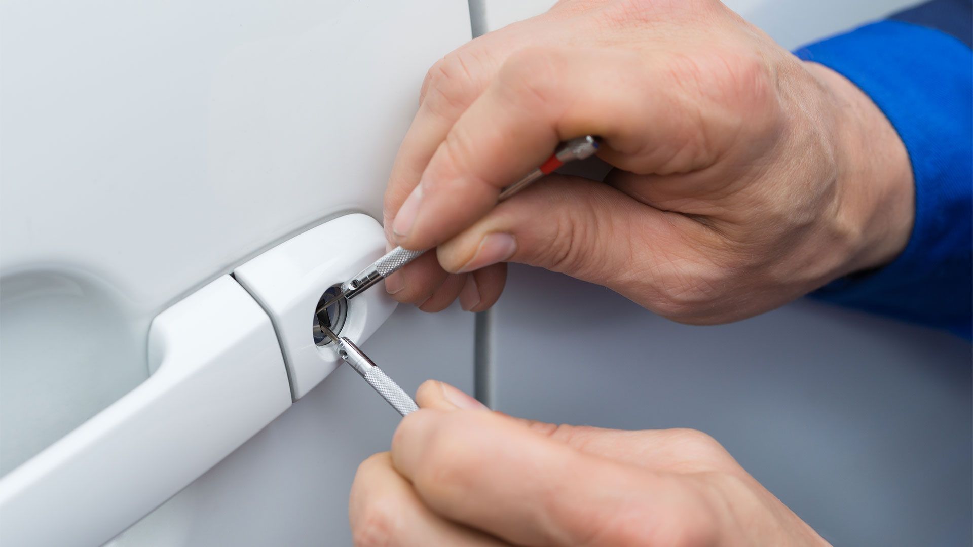 A person is using a screwdriver to fix a car door lock.