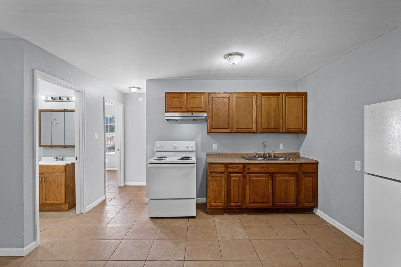 a kitchen with wooden cabinets , a stove , a refrigerator and a sink .