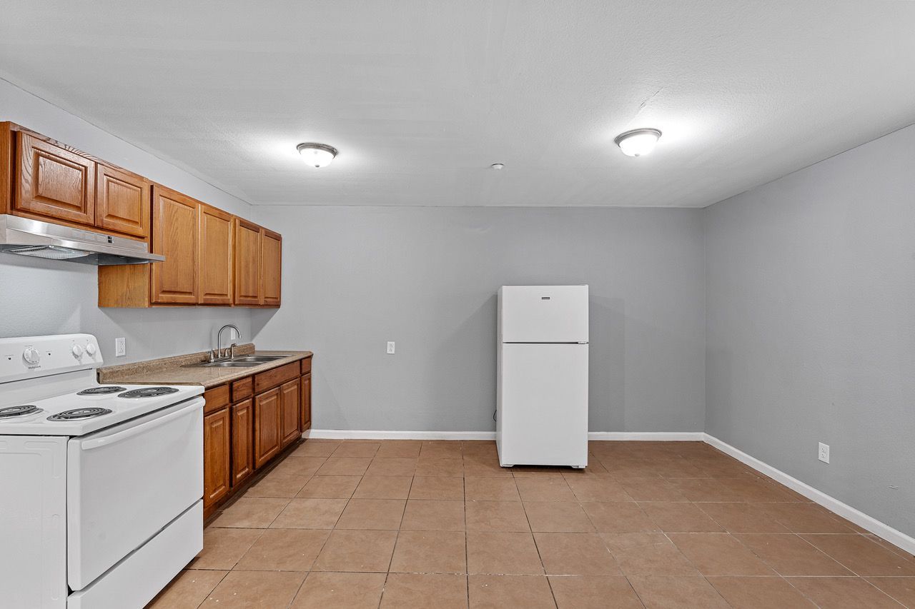 a kitchen with a stove , refrigerator , sink and cabinets .