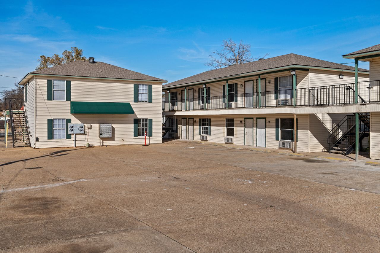 a large apartment building with a large parking lot in front of it .