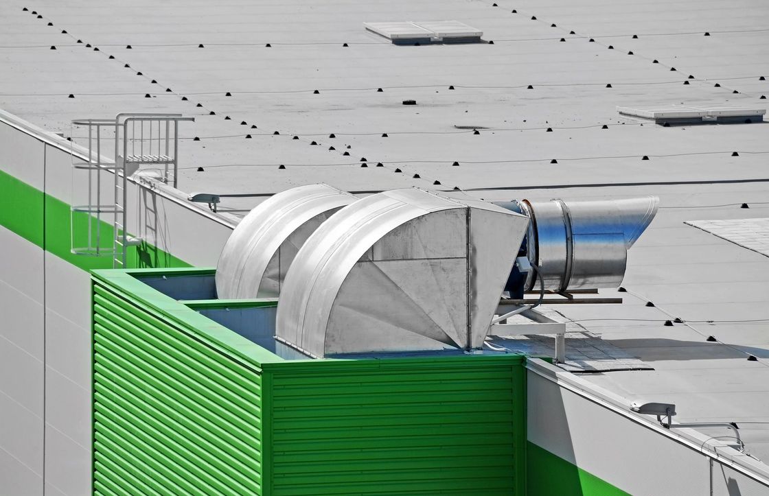 Moderno ufficio con scrivanie bianche, sedie nere e ampie finestre. Pianta in vaso sul davanzale.