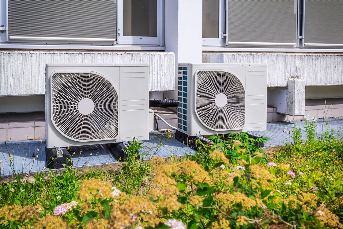 Cucina moderna con mobili in legno e neri, frigorifero in acciaio inox, tavolo da pranzo, lampade a sospensione.