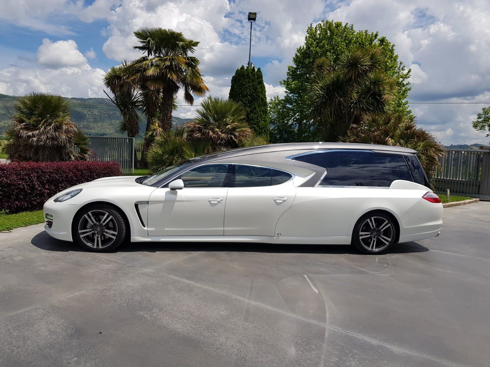 Carro funebre Porsche bianca parcheggiato all'aperto.