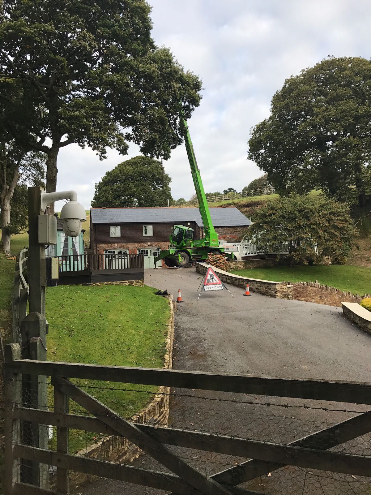 A green crane is sitting in the driveway of a house.