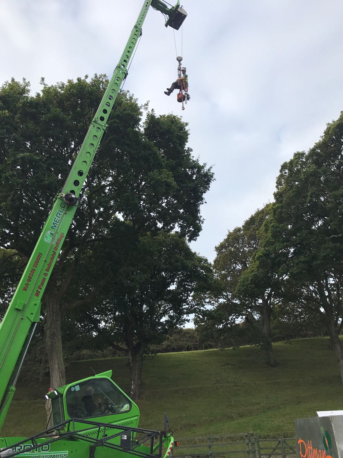 A green crane is lifting a person in the air.