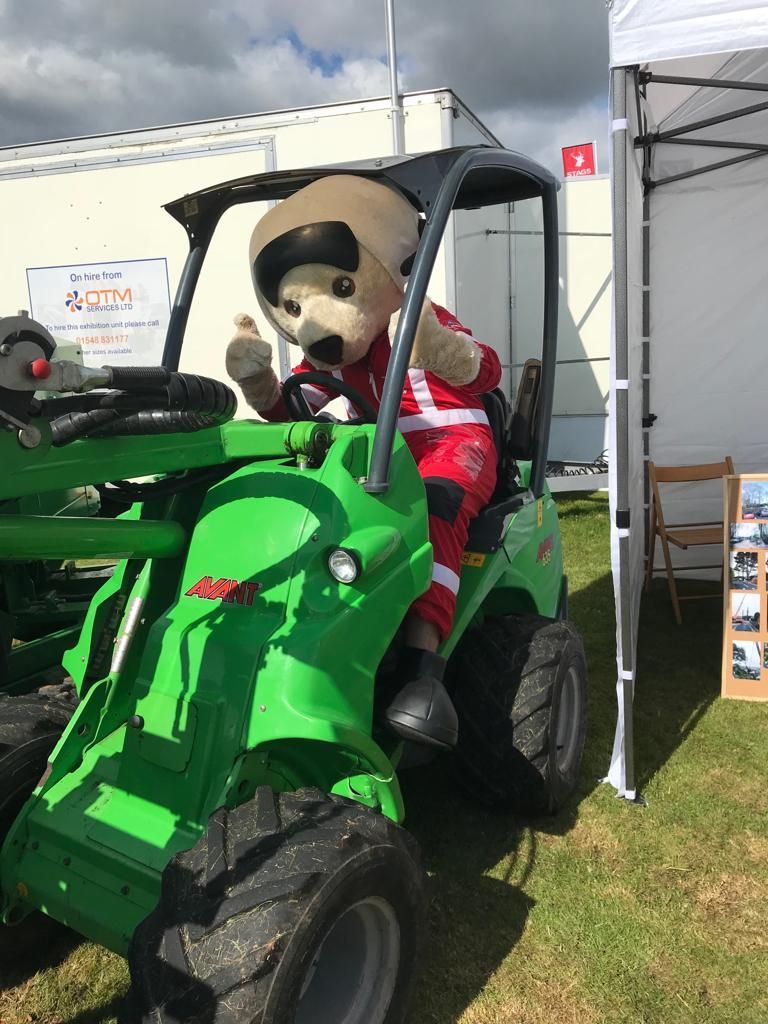 A mascot is sitting in a green tractor.