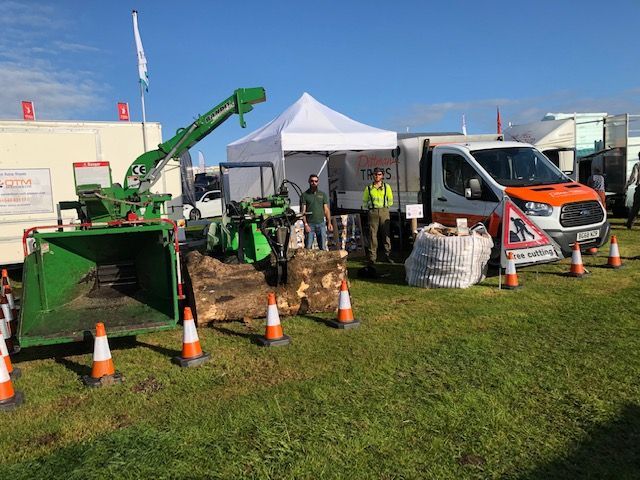 A group of people are standing in a field with a bunch of trucks and machinery.