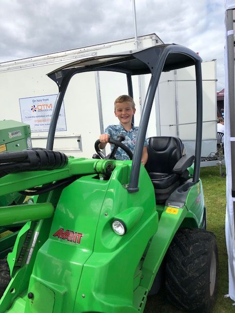 A young boy is sitting in a green tractor.