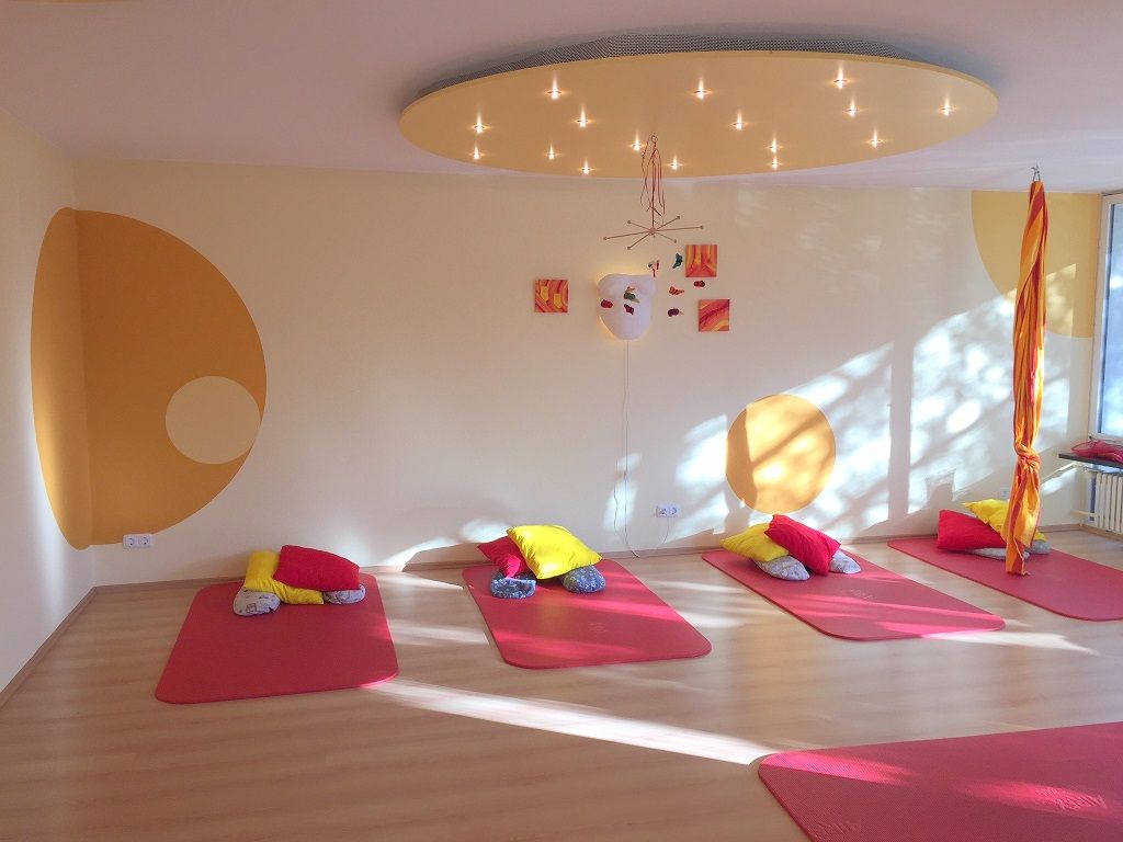 Heller Raum der Praxis mit warmen Farben, dunkelrot und orange mit Holz hauptsächlich.