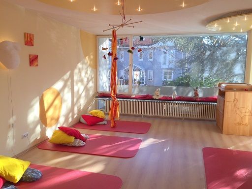 Heller Raum der Praxis mit warmen Farben, dunkelrot und orange mit Holz hauptsächlich.