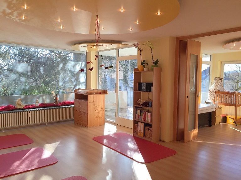 Heller Raum der Praxis mit warmen Farben, dunkelrot und orange mit Holz hauptsächlich.