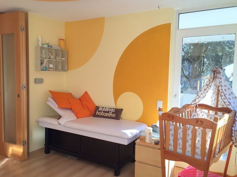 Heller Raum der Praxis mit warmen Farben, dunkelrot und orange mit Holz hauptsächlich.