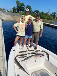 A group of people are standing on the back of a boat with fish on it.