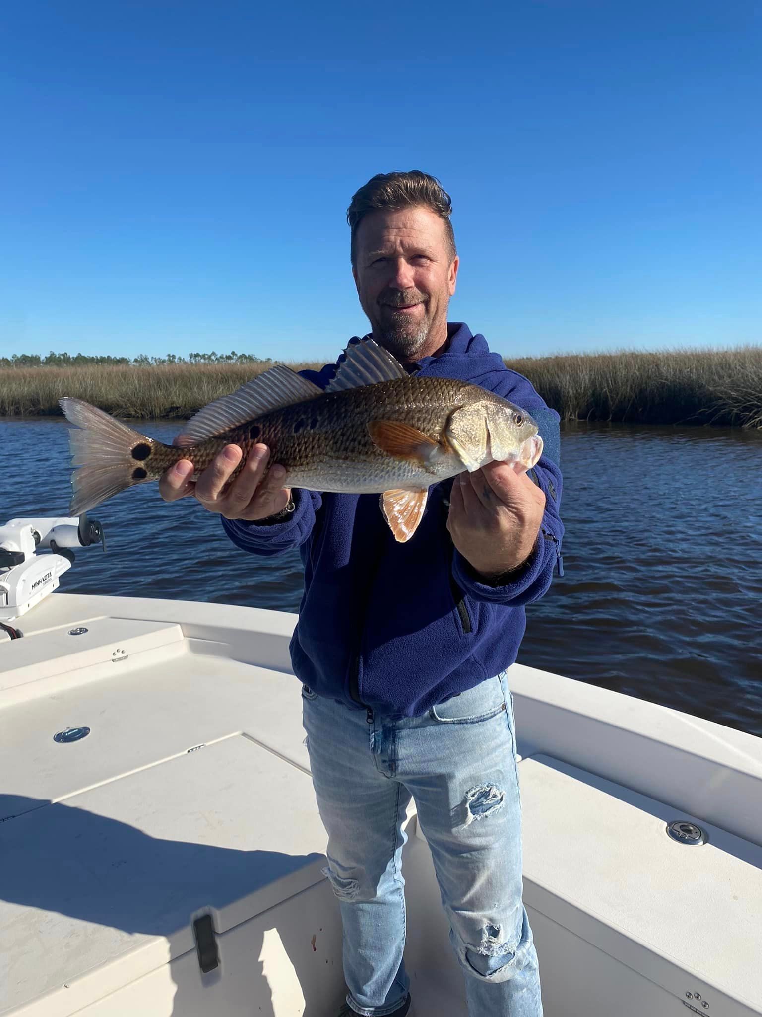 A man is holding a large fish on a boat.