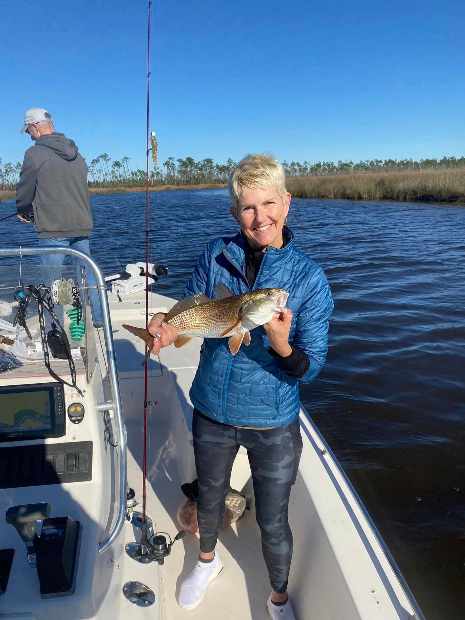 A woman is standing on a boat holding a fish.