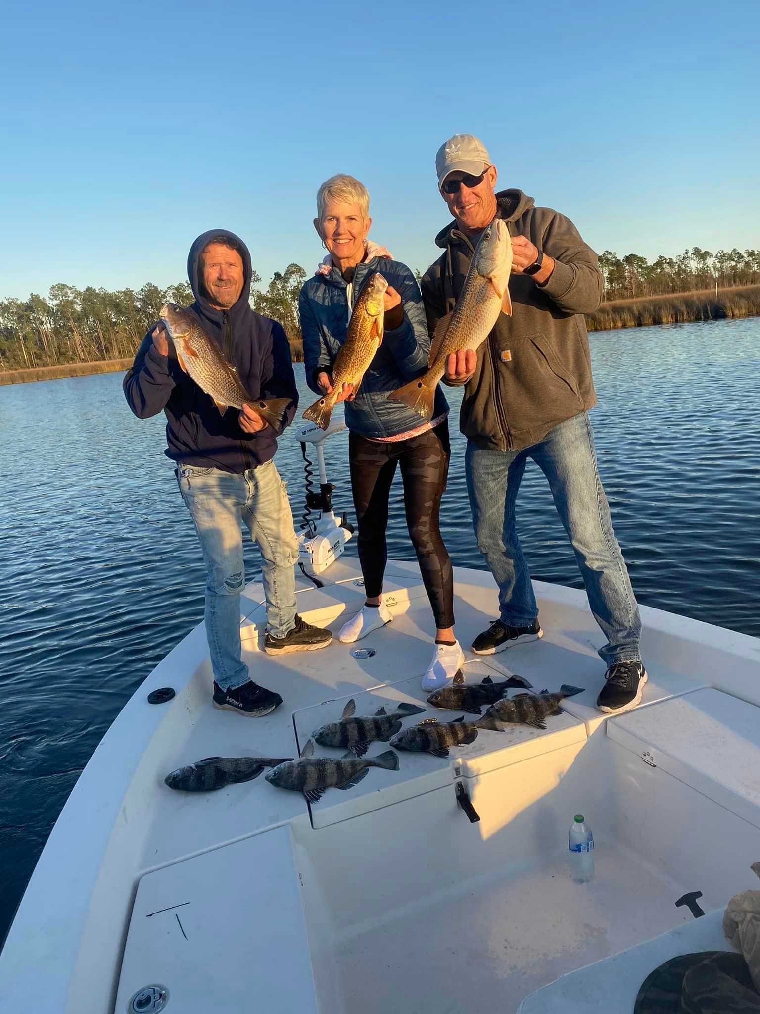 Three men are standing on a boat holding fish.