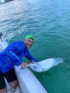 A man is holding a fish on a boat in the water.