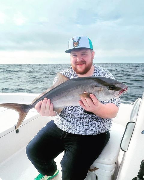 A man is sitting on a boat holding a large fish.