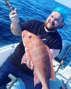 A man is holding a large red fish on a boat.