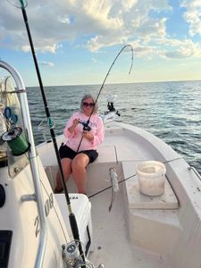 A woman is fishing on a boat in the ocean.