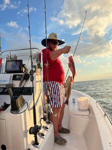 A man is fishing on a boat in the ocean.