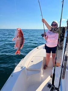 A woman is holding a fish on a boat in the ocean.