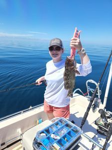 A woman is holding a fish on a boat in the ocean.
