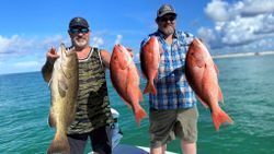 Two men are holding fish on a boat in the ocean.