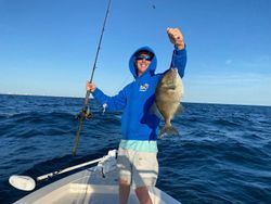 A man is holding a fish on a boat in the ocean.