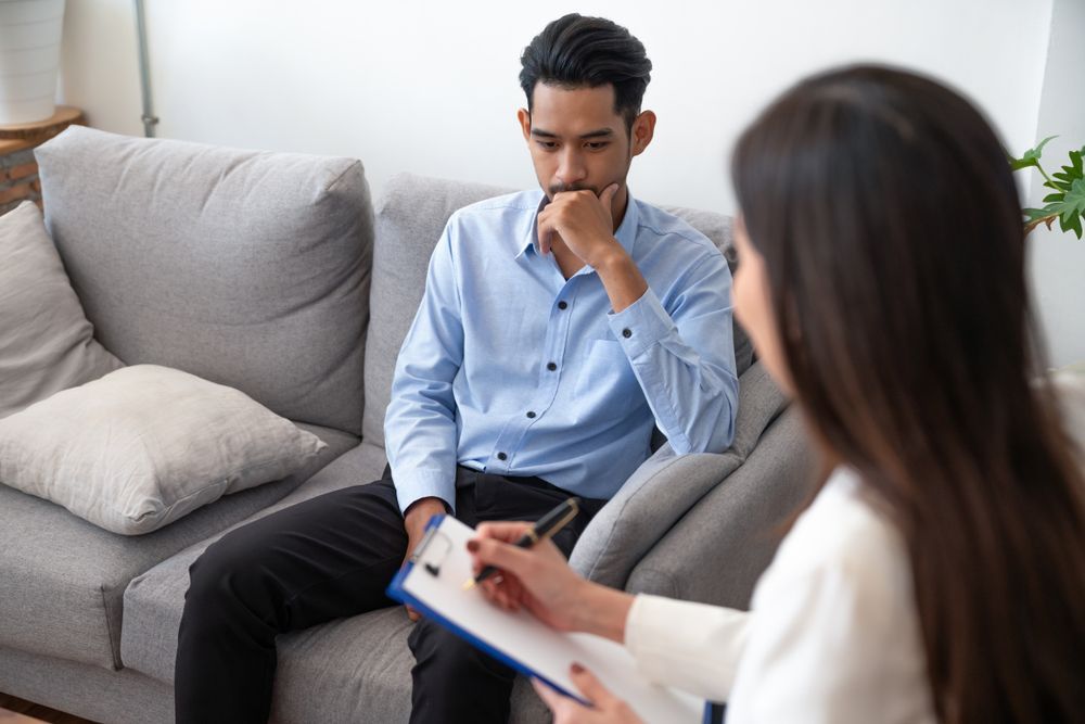 Man in Therapy, Looking Down, Facing a Person With a Notepad — Oracle Psychology Child & Adolescent Psychologists Newcastle in Newcastle, NSW
