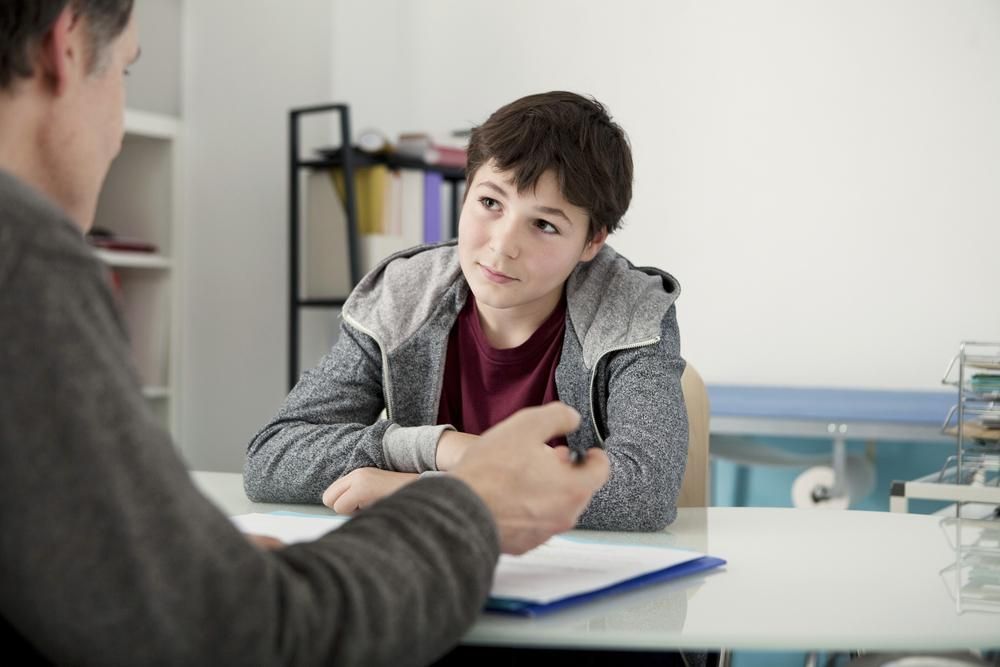 A Young Boy Is Sitting and Talking to A Man — Oracle Psychology Child & Adolescent Psychologists Newcastle in Newcastle, NSW
