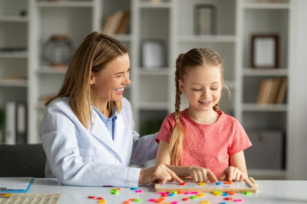 A Woman Is Sitting at A Table with A Girl — Oracle Psychology Child & Adolescent Psychologists Newcastle in Newcastle, NSW
