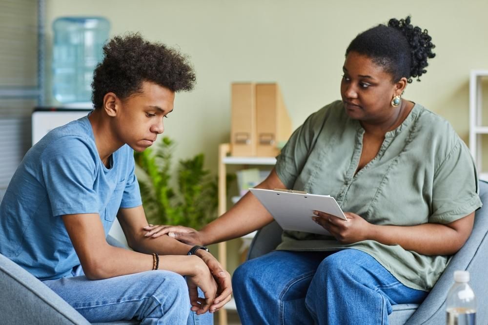 A Woman in A Chair Talking to A Young Man — Oracle Psychology Child & Adolescent Psychologists Newcastle in Newcastle, NSW