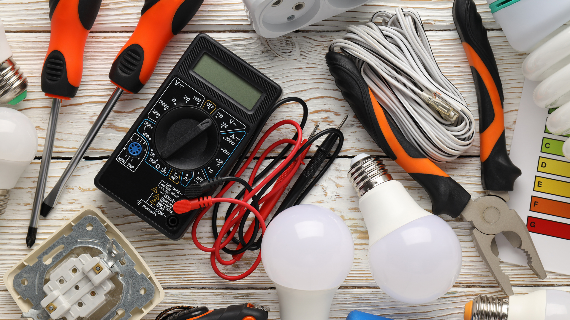 A bunch of electrical tools are on a wooden table.