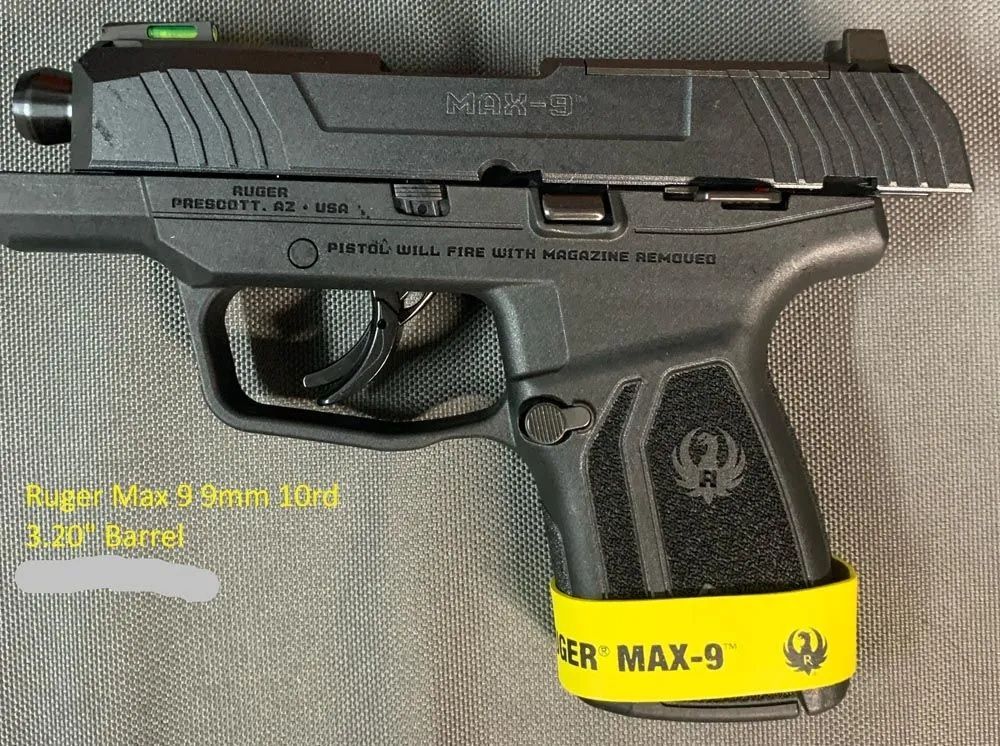 A black ruger max 9mm luger pistol is sitting on a table.