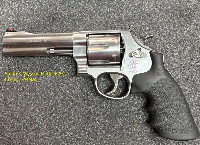 A stainless steel revolver with a black grip is sitting on a foam surface.
